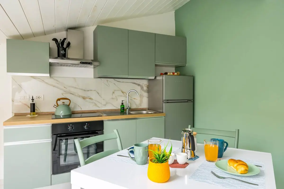 Cucina verde salvia con tavolo apparecchiato per la colazione